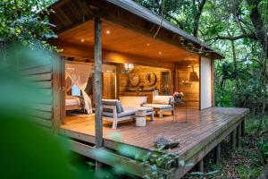 a cabin in the woods with a wooden deck at Summerfields Rose Retreat and Spa in Hazyview