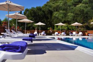 einen Pool mit Liegestühlen und Sonnenschirmen sowie einen Pool in der Unterkunft Angelika Elegant Hotel in Parga