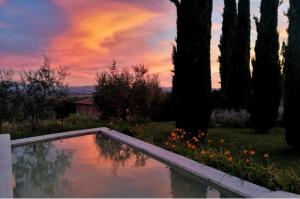 einen Pool im Garten mit Bäumen und Sonnenuntergang in der Unterkunft Villa Mozzafiato con Jacuzzi o Camino Toscana Montepulciano in Valiano