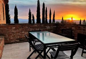 einen Tisch und Stühle auf einer Terrasse mit Sonnenuntergang in der Unterkunft Villa Mozzafiato con Jacuzzi o Camino Toscana Montepulciano in Valiano