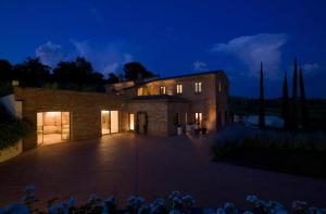 ein großes Backsteinhaus in der Nacht mit Licht an in der Unterkunft Villa Mozzafiato con Jacuzzi o Camino Toscana Montepulciano in Valiano