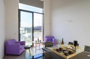 sala de estar con muebles de color púrpura y ventana grande en Loft a Montepulciano sopra Birrificio artigianale, en Abbadia a Isola