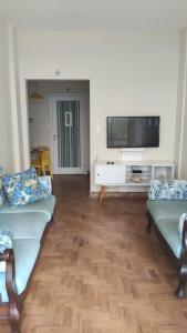 a living room with two couches and a flat screen tv at Apartamento frente ao mar Pitangueiras in Guarujá