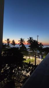 een balkon met uitzicht op het strand bij zonsondergang bij Apartamento frente ao mar Pitangueiras in Guarujá