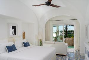 a white bedroom with two beds and a couch at Hotel La Minerva in Capri