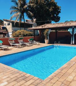 una piscina con sillas y una casa en Búzios Centro Hotel, en Búzios