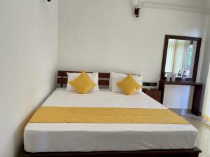a bedroom with a large bed with yellow pillows at Theon Resort in Anuradhapura