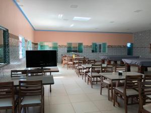 un restaurante con mesas y sillas y TV de pantalla plana en Pousada Portal da Villa, en Vitória da Conquista
