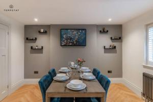 a dining room with a wooden table and blue chairs at STYLISH HOME WITH FREE PARKING - 10 MINS TO LEGOLAND! in Windsor