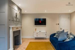 a living room with a blue couch and a fireplace at STYLISH HOME WITH FREE PARKING - 10 MINS TO LEGOLAND! in Windsor