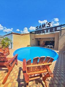 una piscina con 2 sillas de madera y un edificio en Sam'S VIP Hostel San Gil, en San Gil