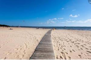 um calçadão que leva a uma praia com pessoas nele em Villa dans résidence privée au bord du lac d'Hourtin port em Hourtin