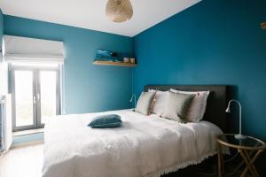 een blauwe slaapkamer met een bed met een blauwe muur bij Hoeve de Reetjens - Le Grenier in Bilzen