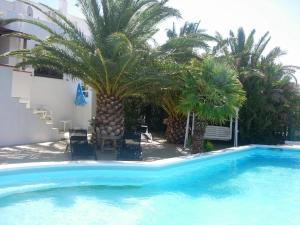 a blue swimming pool with palm trees and chairs at Villa Francesca in Flumini di Quartu