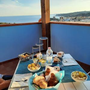 een tafel met borden eten op een balkon bij B&B Monte Becco in Santa Teresa Gallura