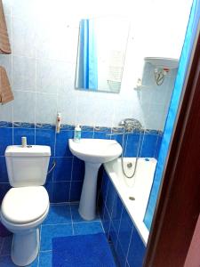 a blue tiled bathroom with a toilet and a sink at Уютные апартаменты c кондиционером на Уманчанке in Umanʼ