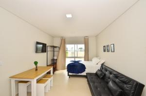 um quarto com uma cama, um sofá e uma mesa em InHome - Estúdio 02, conforto e aconchego no Campeche N1518 em Florianópolis