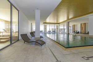 a pool in a building with a chair and a couch at Aparthotel Waterkant Suites - Fewos am Meer mit SPA in Börgerende-Rethwisch