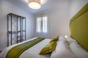 una camera da letto con un grande letto bianco con cuscini verdi di JCL first apt in the hearth of Florence a Firenze