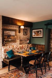 a dining room with a table and a couch at Cat and Custard Pot Inn in Shipton Moyne