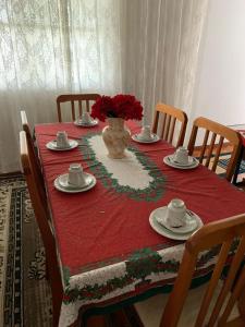 einen Tisch mit einem roten Tischtuch und einer Blumenvase in der Unterkunft Casa de hospedagem providências in Cachoeira Paulista