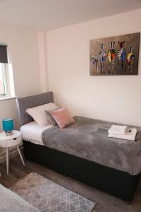 a bedroom with a bed and a painting on the wall at Blue Apartment, 2 Bedroom with Balcony, Netflix in Peterborough