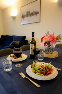 a table with two plates of food and a bottle of wine at Blue Apartment, 2 Bedroom with Balcony, Netflix in Peterborough