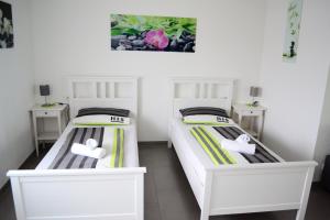 two beds in a small room with white beds at Ferienwohnung am Seewald in Meckenbeuren