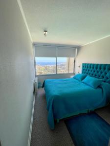 a bedroom with a blue bed and a large window at Edificio En Reñaca in Viña del Mar
