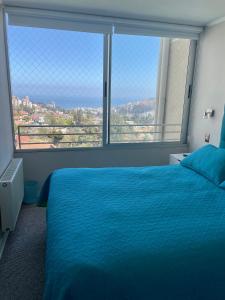 um quarto com uma cama azul e uma grande janela em Edificio En Reñaca em Viña del Mar