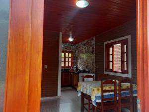 a dining room with a table and a kitchen at Recanto Três Irmãs, chalé 2 in Camanducaia