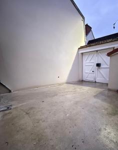 an empty garage with white walls and white garage doors at Les Gouttes d'Or in Pierry