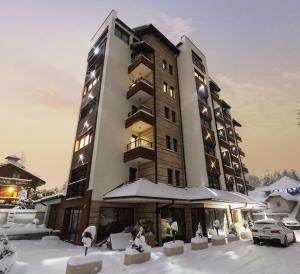 a tall building with snow on the ground at Zlatibor Apartman Aria Forest Spa & Gym in Zlatibor