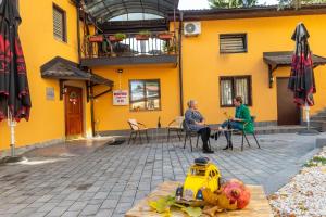 deux femmes assises à une table devant un bâtiment jaune dans l'établissement Hotel Vamos Sarajevo, b&b, à Sarajevo