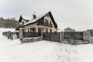 a house in the snow with a fence at Apartament Między Górami in Kacwin