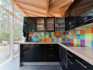 een keuken met zwarte kasten en kleurrijke tegels op de muur bij Idyllically located Holiday Home in Norg with Sauna in Norg