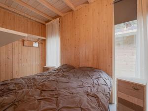 ein Schlafzimmer mit einem Bett in einer Holzwand in der Unterkunft Idyllically located Holiday Home in Norg with Sauna in Norg