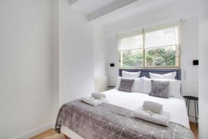 ein weißes Schlafzimmer mit einem großen Bett mit grauen und weißen Kissen in der Unterkunft TROCADERO/ EIFFEL TOWER - 3 Bedrooms- All New! in Paris