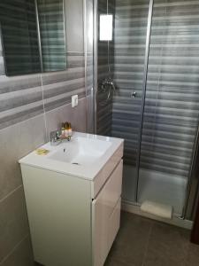 a bathroom with a white sink and a shower at PoolSeaView Spacious House in Atouguia da Baleia