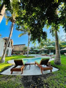 a resort pool with two lounge chairs and palm trees at Casa Mandala Hotel in Pijijiapan