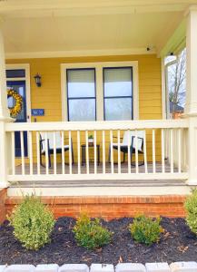a yellow house with a white railing on a porch at Vine City Bee Hive in Atlanta