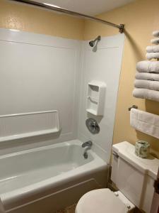 a bathroom with a white tub and a toilet and towels at Travelers Lodge Beatrice in Beatrice