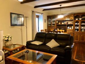 a living room with a black leather couch and a table at Apartamento Rural Areso - Fraxkuenea in Areso