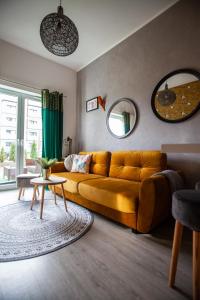 a living room with a yellow couch and a table at Apartament Panorama De Lux Family in Koszalin