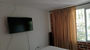 TV de pantalla plana en la pared de un dormitorio en Apartamento Amoblado en Ibagué, en Ibagué