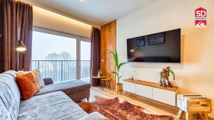ein Wohnzimmer mit einem Sofa und einem TV in der Unterkunft Apartament Bella Vista z Sauną ogólnodostępną - 5D Apartamenty in Świeradów-Zdrój
