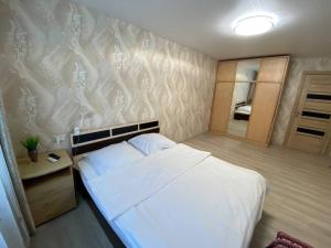 ペトロパブロフスク・カムチャツキーにあるWELCOME HOME Aparts & Tours 1233 Бесконтактное заселениеの白いベッドと壁が備わるベッドルーム1室が備わります。