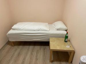 Una cama pequeña y una mesa con una botella. en Relax Hotel-Ludwigshafen en Ludwigshafen am Rhein