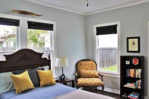 Schlafzimmer mit einem Bett, einem Stuhl und Fenstern in der Unterkunft CasaMagnolia - Cheerful 3-bdrm home, free parking, 30 days or more in San Antonio