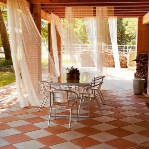 um pátio com uma mesa e cadeiras num piso de azulejo em Cameloth B&B em Settimo Rottaro